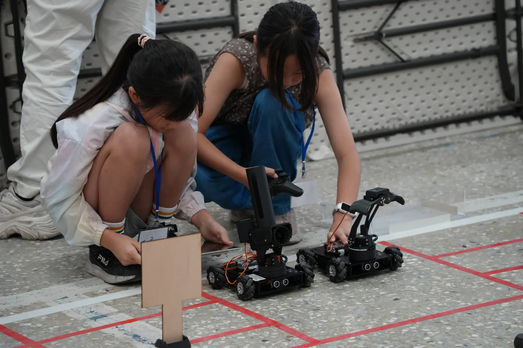 兩位學生蹲在地上調整自走車